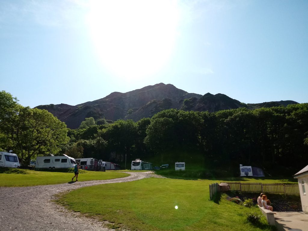 The picture shows Wern Caravan and camping park, the road leading through the park with lush green grass on either side.